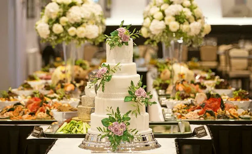 Tiered wedding cake in front of a lavish reception buffet